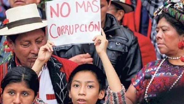 Indigenous protesters carry a sign that reads "No more corruption."
