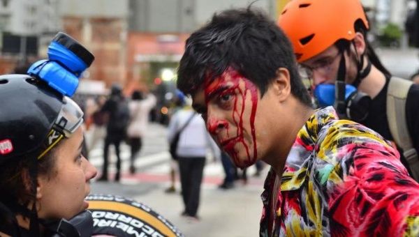 People attend to a demonstrator injured in a violent crackdown by police in Sao Paulo, Brazil, Jan. 13, 2016.