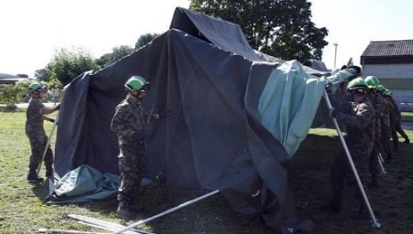 Swiss Army personnel build a tent outside a refugee camp in Lyss, Switzerland, Sept. 2, 2015.