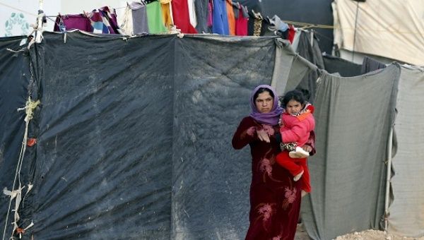 A Syrian refugee woman carrying her child looks at the convoy of U.N. High Commissioner for Refugees, January 18, 2016. 
