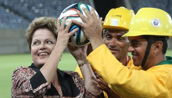 Brazilian President Dilma Rousseff (L) holds a soccer ball with workers during the inauguration of the Arena das Dunas stadium in Natal, Brazil, Jan. 22, 2014.