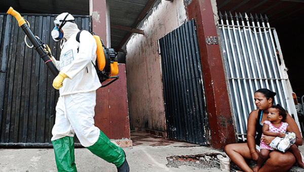 A health official walks past residents as he carries out fumigation to help control the spread of Chikungunya and dengue fever, Mar.6, 2015