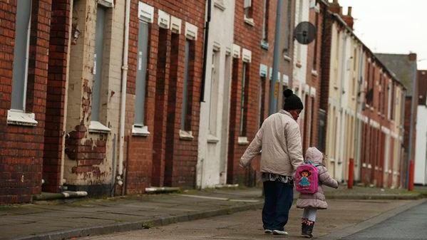 A woman and child walk along a terraced street in the Gresham area of Middlesbrough.