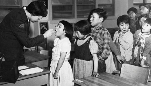 Nurse Desrochers checks a girl's throat while other children wait in line, at the Frobish Bay Federal Hostel in Iqaluit, Nunavut, in a 1959 archive photo.