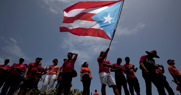 A man waves a national flag as others stand nearby during a protest in San Juan in this May 13, 2015 file photo.