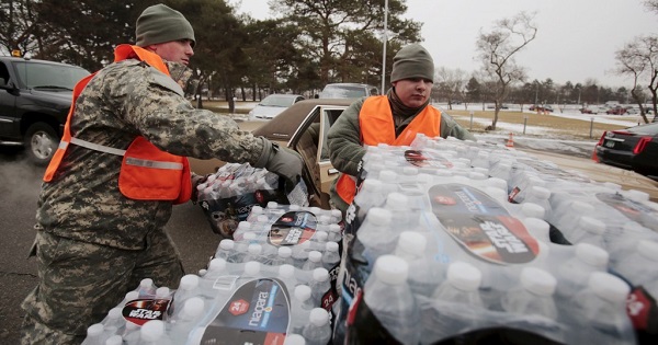 Michigan National Guard members help to distribute water to a line of residents in their cars in Flint, Michigan, on Jan. 21, 2016.