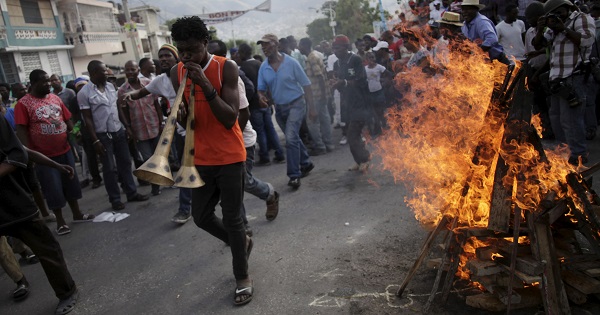A protester walks next to a fire lighted for a ceremony during a demonstration against the government in Port-au-Prince, Haiti, Jan. 25, 2016.