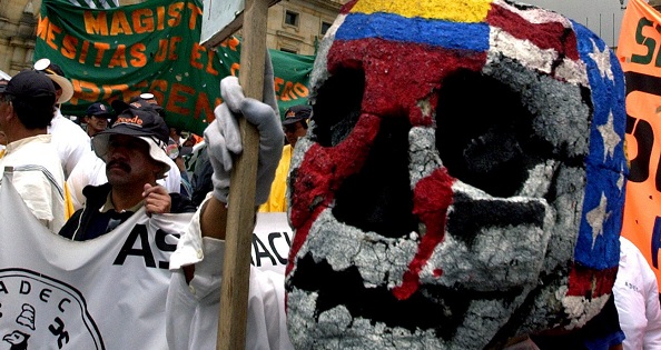 A worker with a mask with the U.S. and Colombian flags painted on it protests in the Plaza Bolivar in Bogota, Colombia.