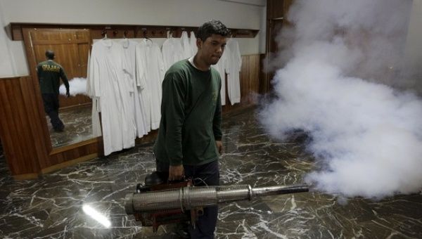 A municipal worker fumigates inside the parsonage of a church to help control the spread of the mosquito-borne Zika virus in Caracas.