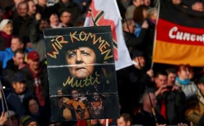 Supporters of the anti-Islam movement PEGIDA hold a poster depicting German Chancellor Angela Merkel with text reading 'We are coming, mommy!' during a demonstration in Germany, Feb. 6, 2016.