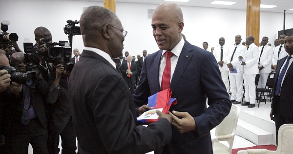 Haiti’s President Michel Martelly gives the presidential sash to the Senate President Jocelerme Privert during a ceremony in Parliament Feb. 7, 2016.