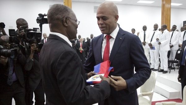 Haiti’s President Michel Martelly gives the presidential sash to the Senate President Jocelerme Privert during a ceremony in Parliament Feb. 7, 2016.