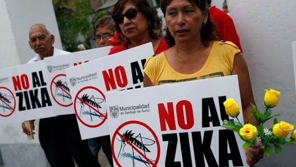 Residents hold signs against zika virus during a fumigation to prevent Zika and other mosquito-borne diseases in Lima, Peru, Feb. 5, 2016.