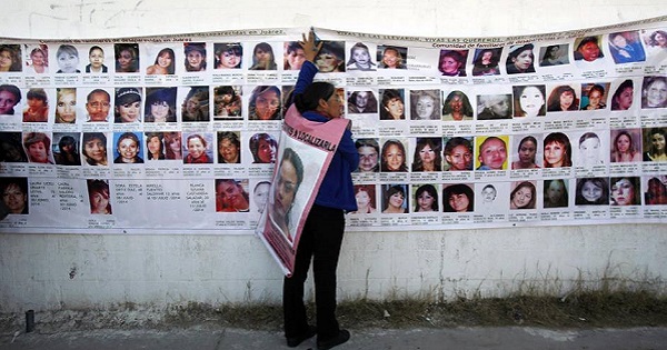 A woman holds onto a banner with the photographs of missing women in Ciudad Juarez Jan. 28, 2015.