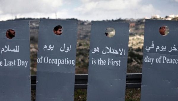 Israeli and Palestinian peace activists walk behind cardboard cut-outs depicting the Israeli controversial separation barrier during a peace march.