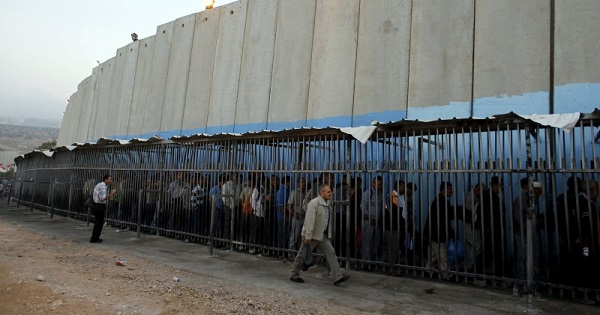 Palestinians wait to cross into Jerusalem next to Israel's controversial barrier at an Israeli checkpoint in the West Bank town of Bethlehem.