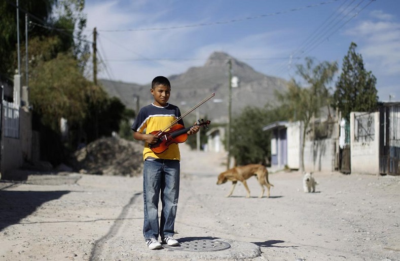 Ten-year-old Jose Angel holds his violin while posing for a photograph on a street in his neighborhood in Ciudad Juarez, October 15, 2010. In one of the world's deadliest cities, a former heroin addict is changing lives with violins and trumpets rather than assault rifles. 