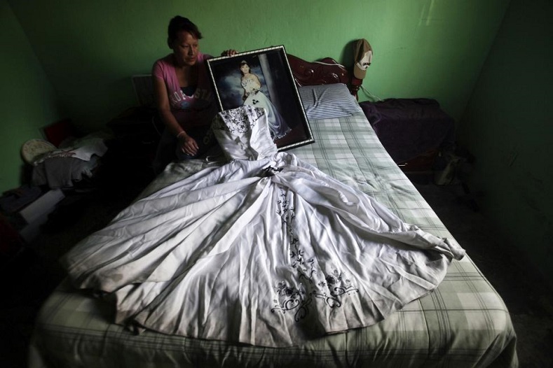 Luz Elena Munoz holds a photograph of her daughter Nancy Ivette Navarro Munoz while sitting next to the dress of Nancy's 15th birthday celebration, in Ciudad Juarez June 3, 2014. Nancy was 18 years old when she disappeared in July 2011 while looking for work in downtown Ciudad Juarez.