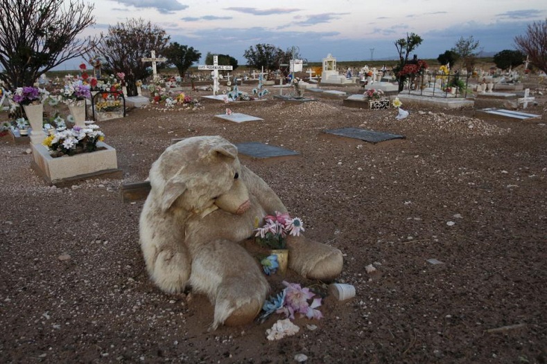 A stuffed bear lies over a child's grave at the children's section of the San Rafael cemetery in Ciudad Juarez July 17, 2011.