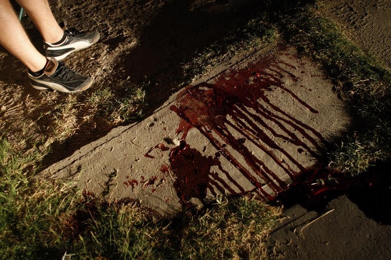 A resident stands next to bloodstains of a man who was gunned down by unknown assailants in the border city of Ciudad Juarez March 3, 2009. 