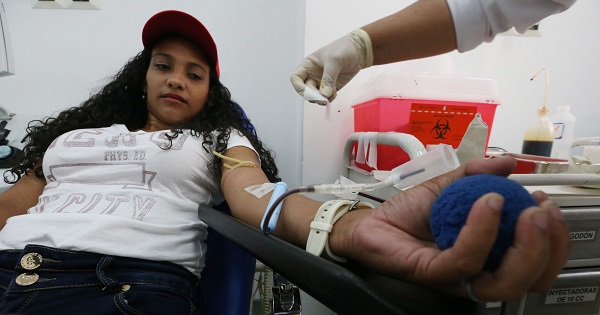 A woman gives blood in Venezuela, where hospitals provide free health care that has helped millions of low-income people access care.