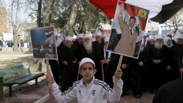 A Druze boy holds a placard showing Syrian President Bashar Assad during a rally in the Israeli-occupied Golan Heights, Feb. 14, 2016.