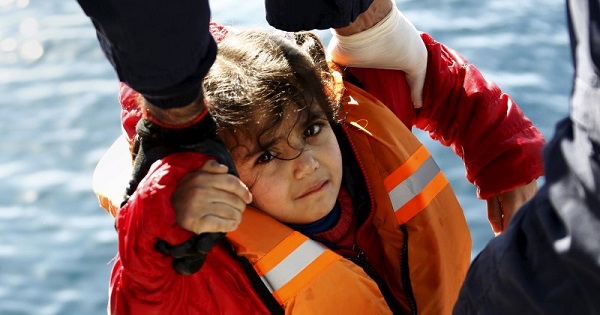 Greek Coast Guard officers move a girl from a dinghy carrying refugees during a rescue operation at open sea, Feb. 8, 2016.
