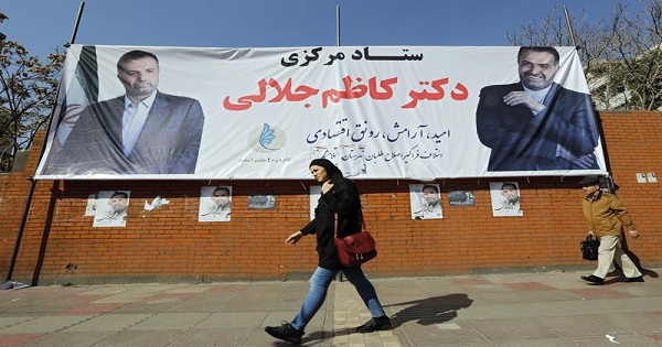 An Iranian woman walk past parliamentary election banners, in Tehran, Iran, Feb. 24, 2016.