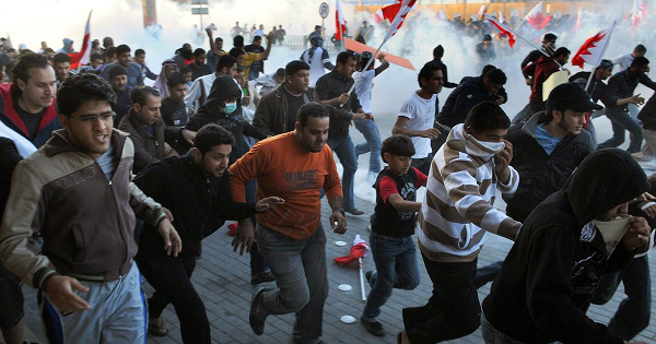 Bahraini protesters run for cover from tear gas fired by police to disperse them in the village of Sanabis near Manama on Feb. 14, 2011.
