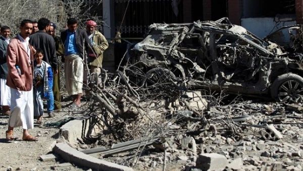 Yemenis inspect damaged vehicles following an airstrike on Sanaa, on February 27, 2016.
