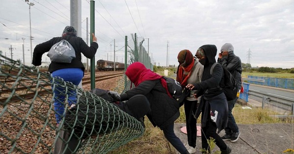 Migrants make their way across a fence near near train tracks as they attempt to access the Channel Tunnel in Frethun, near Calais, France, July 29, 2015.