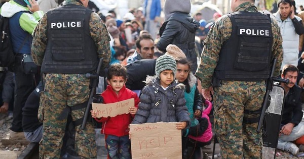 Refugees' children stand among police officers as their families wait to cross the border from Greece into Macedonia, near Gevgelija, Macedonia Nov. 24, 2015.