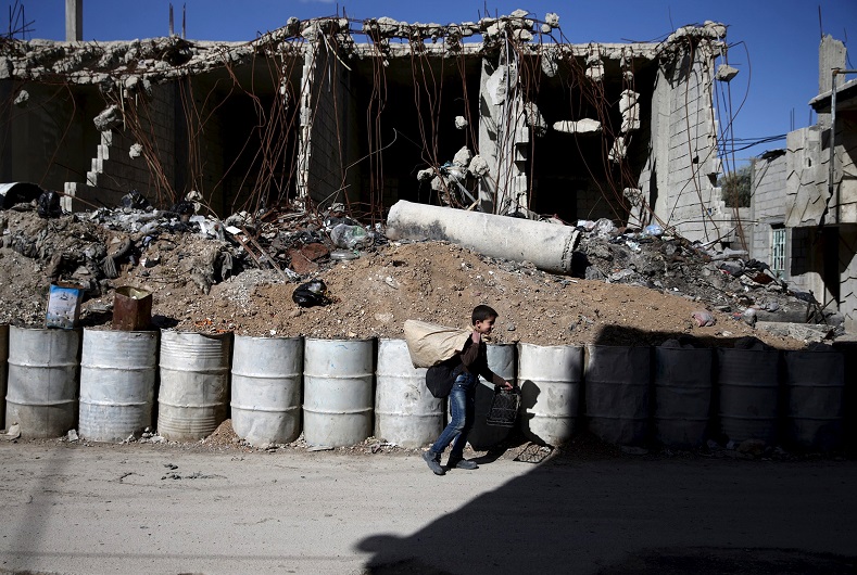 A boy walks past a damaged building in the rebel-held Tishreen neighborhood of Damascus, March 14, 2016.