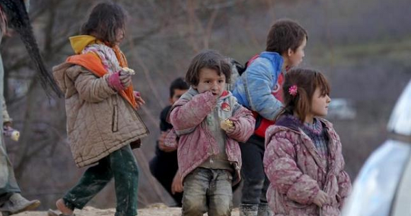 Internally displaced children, covered with mud, wait with their families as they are stuck in the town of Khirbet Al-Joz, in Latakia countryside, Syria, Feb. 7, 2016.