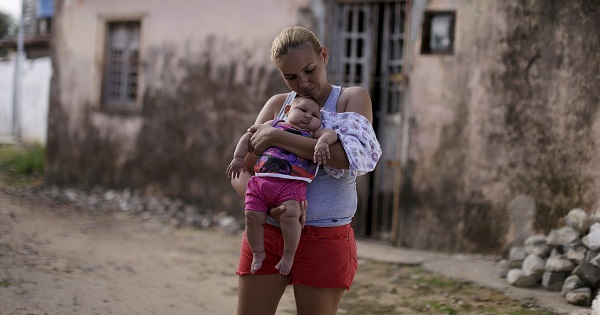 Gleyse Kelly da Silva holds her daughter Maria Giovanna, who has microcephaly, in front their house in Recife.