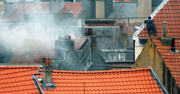 A masked Belgian policeman secures the area from a rooftop above the scene where shots were fired during a police search of a house in the suburb of Forest near Brussels, Belgium, March 15, 2016.