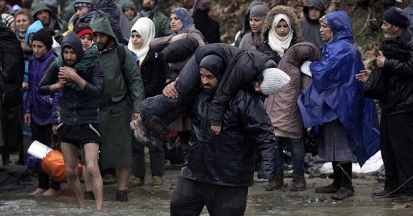 Refugees and migrants cross a river near the Greek-Macedonian border, March 15, 2016.