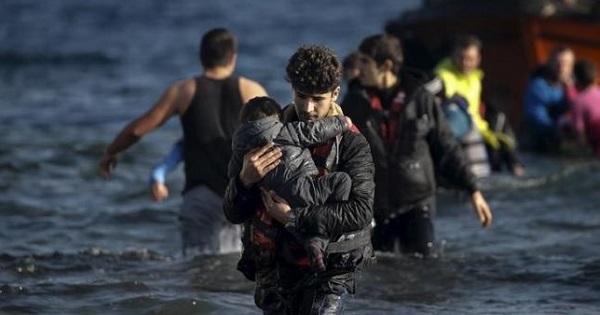 A young man carries a child as refugees and migrants arrive on a boat on the Greek island of Lesbos, Nov. 7, 2015