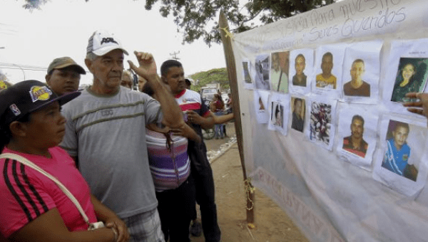 People look at displayed pictures of missing miners in Tumeremo in Bolivar state, Venezuela, March 7, 2016.