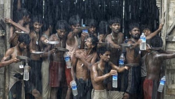 Migrants, who were found at sea on a boat, collect rainwater during a heavy rain fall at a temporary refugee camp near Kanyin Chaung jetty, outside Maungdaw township, northern Rakhine state, Myanmar June 4, 2015