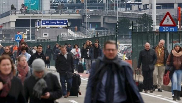 People leave the scene of explosions at Zaventem airport near Brussels, Belgium.