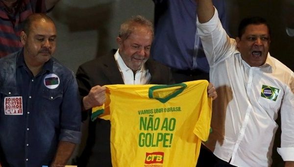 Former Brazilian President Luiz Inacio Lula da Silva holds a T-shirt that reads 