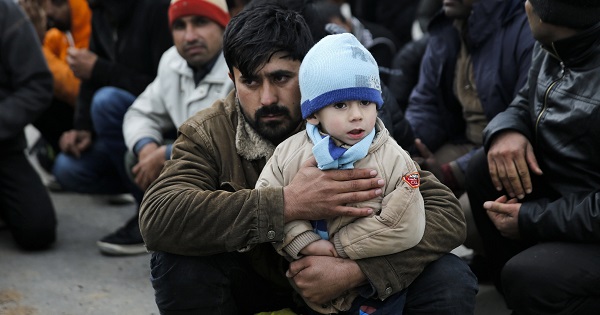 An Afghan migrant holds his son as they wait to be transferred to Moria after arriving on the Greek island of Lesbos, March 22, 2016.