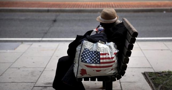 A homeless woman sits on a bench a few blocks away from the White House in downtown Washington, Sept. 1, 2015.