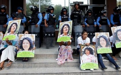 Indigenous people hold posters of Berta Caceres while sitting in front of riot police during a protest to demand justice in Tegucigalpa, Honduras, March 17, 2016. 