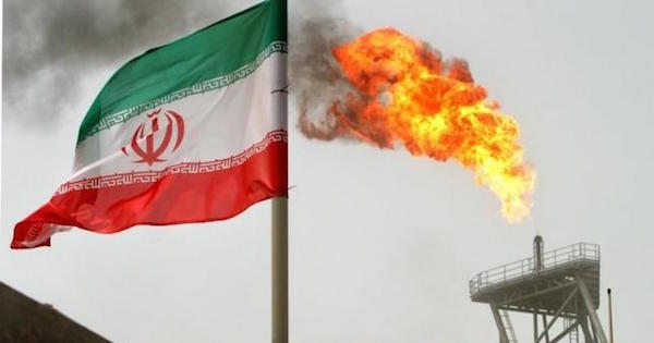 Gas flares from an oil production platform at the Soroush oil fields with an Iranian flag in the foreground in the Persian Gulf, 776 miles south of Tehran.