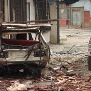 A woman passes a destroyed car March 28,1999, after a NATO missile hit downtown of Kosovo's capital of Pristina in Saturday night's NATO attack.