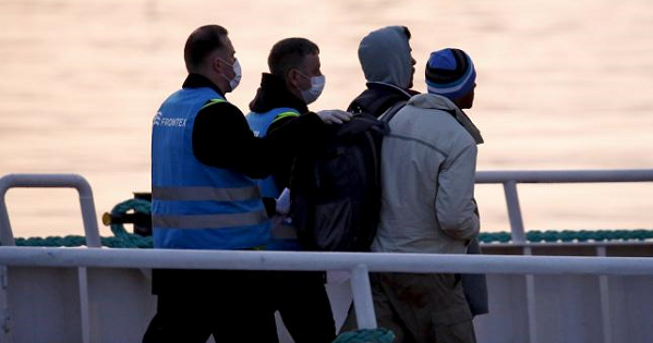 Frontex officers escort migrants boarding on a Turkish-flagged passenger boat to be returned to Turkey, on the Greek island of Lesbos, April 4, 2016.