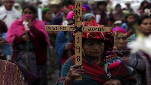 An Indigenous woman holds a cross during a march to commemorate the National Day of Dignity for the Victims of Armed Internal Conflict.
