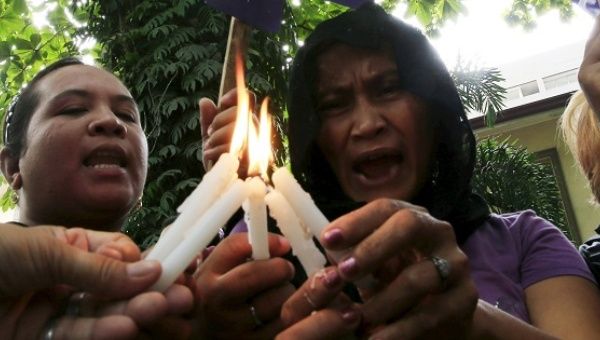 Activists light candles and offer prayers during a memorial ceremony in Manila.